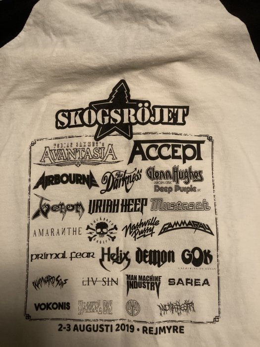 Vit T-shirt med tryck; musikfestival; bandnamn; "Skogsröjet"; datum; svarthvitt; rock; heavy metal; Rejmyre; 2019.