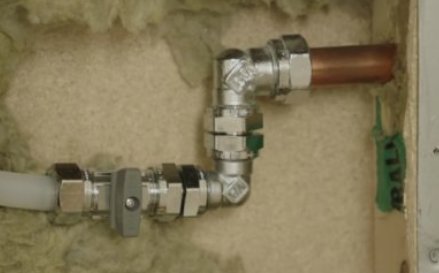 VVS-installation med kopparledningar, förbindelsestycken och isolering i en väggstruktur.