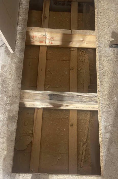Öppet golv med trästomme och isolering synligt i ett pågående byggprojekt.