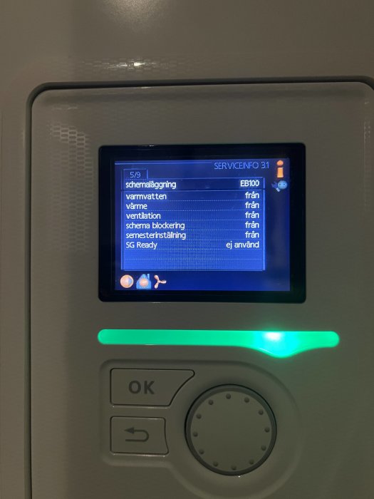 Display av uppvärmningssystem, meny för inställningar, navigeringsknappar, grönt statusljus, grå bakgrund.
