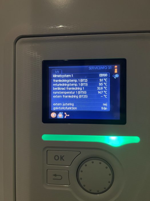 Display för värmesystem visar temperaturinformation och inställningar, inramat av maskinpanel.