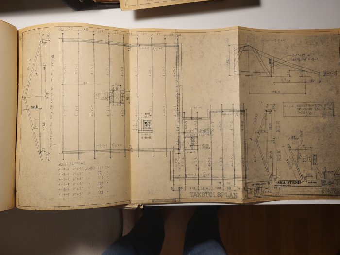 Uppslagen bok med arkitektoniska ritningar, troligen för en byggnad. Mätningar och anteckningar synliga.