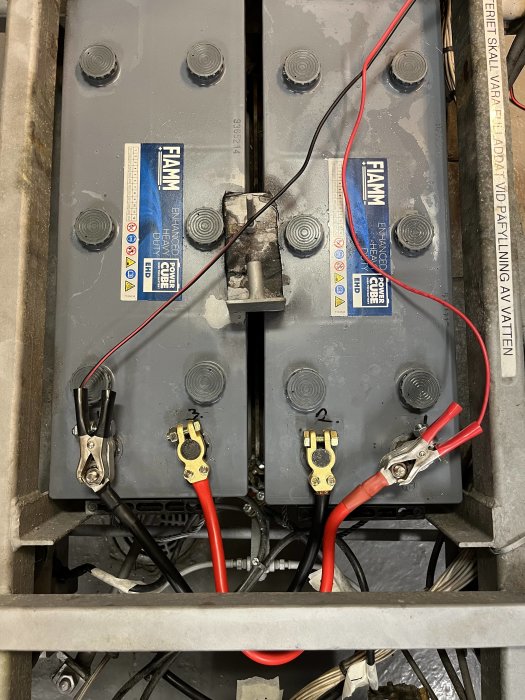 Industriell batterianordning med kablar, säkringsblock och varningsetiketter, troligen del av större maskin eller system.