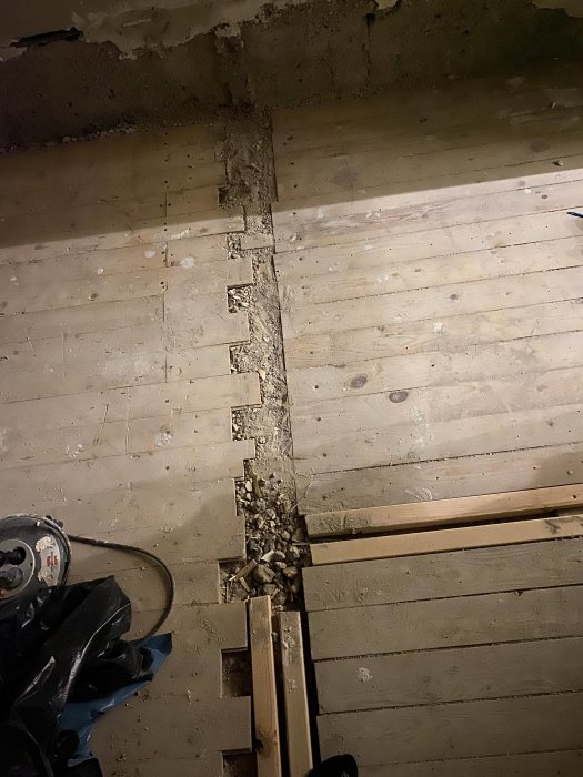 Renovering, upprivet golv, betong och trä, byggdamm och verktyg.