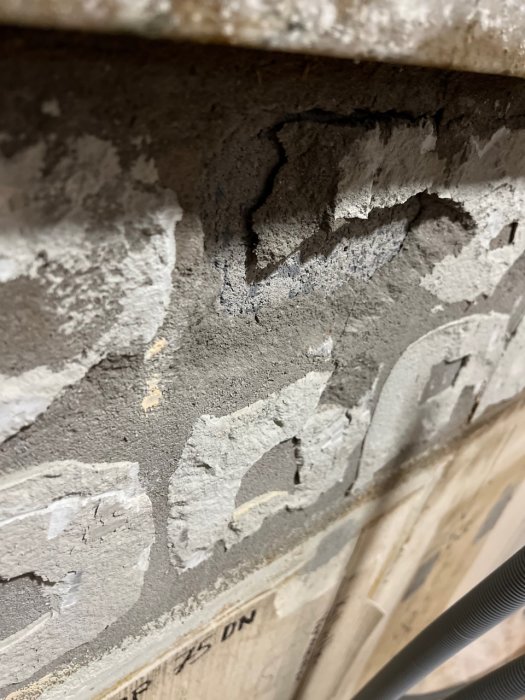 Närbild av grov betongvägg med slarvigt applicerat spackel eller puts på en byggarbetsplats.