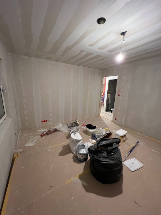 Omfattande renovering pågår, skräp och byggmaterial överallt, väggar och tak i gipsskivor, ej färdigmålade.