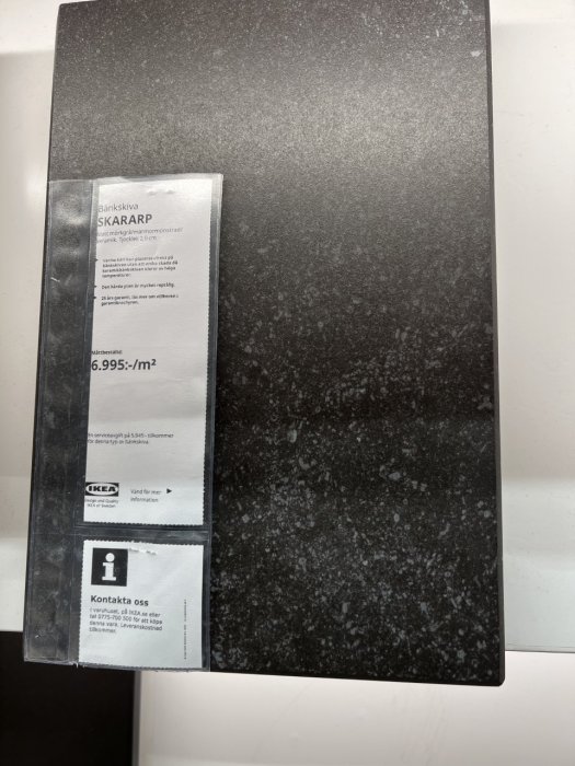 Svart marmorerad bänkskiva, SKARARP från IKEA, etikett med pris och information, kontaktuppgifter, på vit bakgrund.