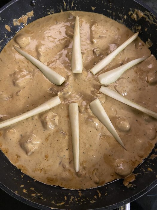 Matlagning: brunsås med köttbullar och skivad vit sparris, i stekpanna.