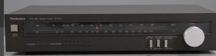 Svart Technics FM/AM stereo tuner, frekvensskala, vred, knappar, retro hi-fi utrustning.