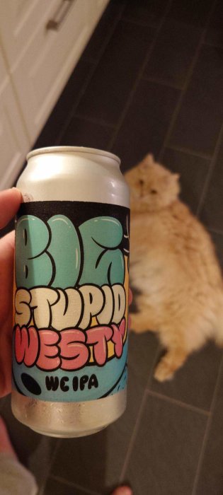 En burk med text framför en suddig katt på ett golv.