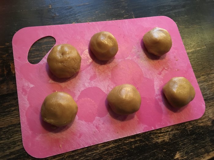 Sex runda degklumpar på ett rosa skärbräde, bakförberedelse, kök, hemlagat, träbord.