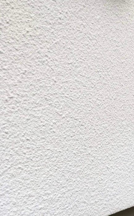 Vit strukturerad yta, troligen en vägg, diagonal komposition, närbild, inga distinkta objekt.