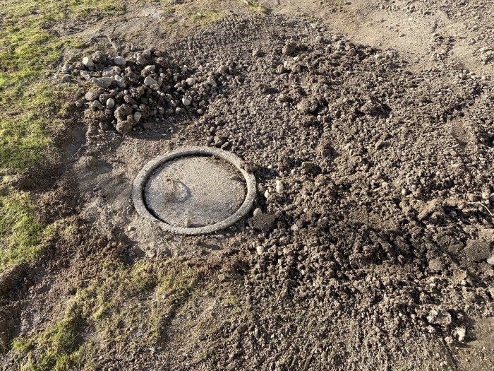 Gummi i marken, jordhögar runtomkring, gräs kantar, möjligt grävarbete eller markarbeten, utomhus under dagtid.