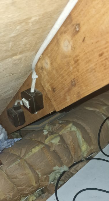 Vind, isolering, träbjälkar, elektriska ledningar, gamla säkringsdosor. Oorganiserat, potentiellt brandfarligt, omodern elinstallation.