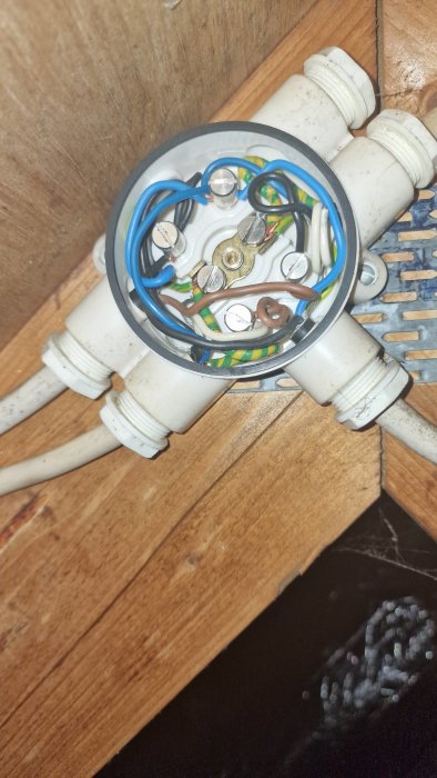 Elanslutningar i dosa, kablar, skruvanslutning, vägggenomföringar, träunderlag, otydlig bakgrund, elektrisk installation.