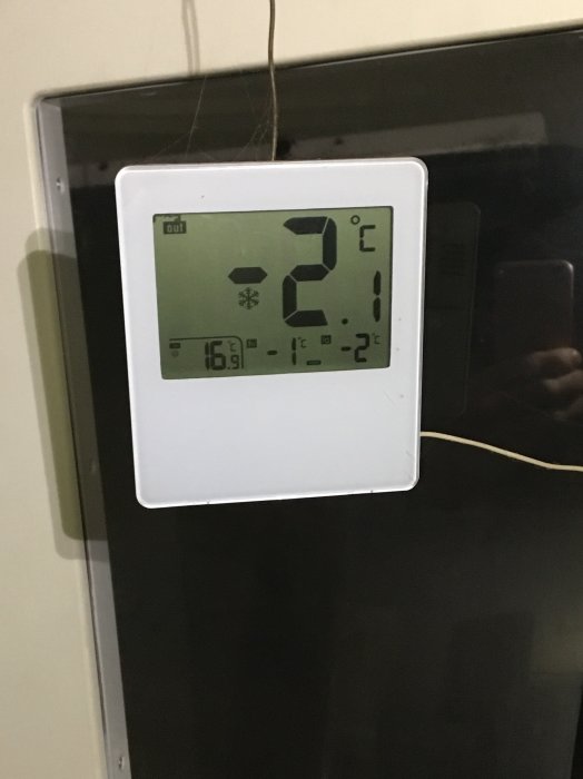 Digital termometer visar utomhustemperatur minus 2 grader Celsius, inne 16,2 grader. Kyligt väder. Speglig bakgrund.