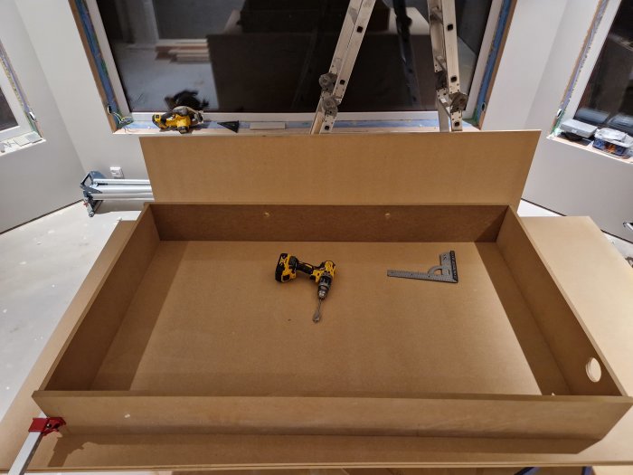 Inomhusrenovering, träskåp under konstruktion, elverktyg, vinkelhake, stege, blivande klädskåp eller förvaring.