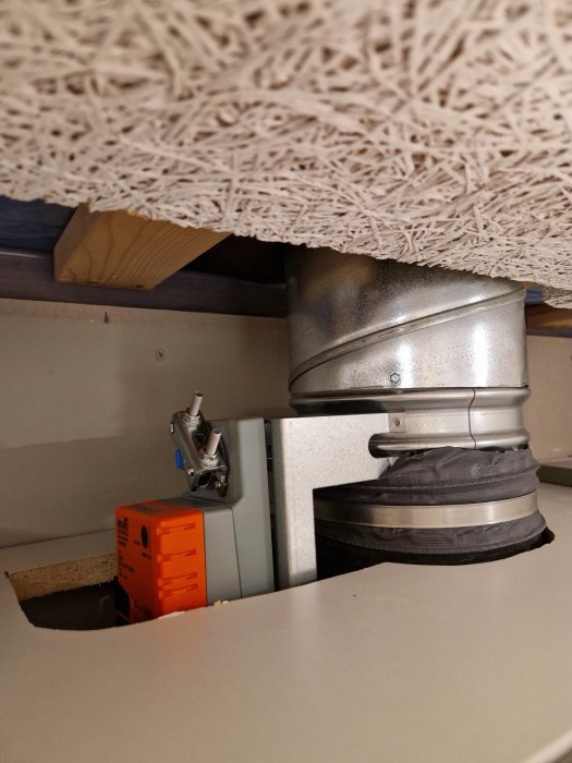 Ventilationskanalsystem under träbänk, förseglad med tejp, bredvid elektrisk kretsbrutenhet.