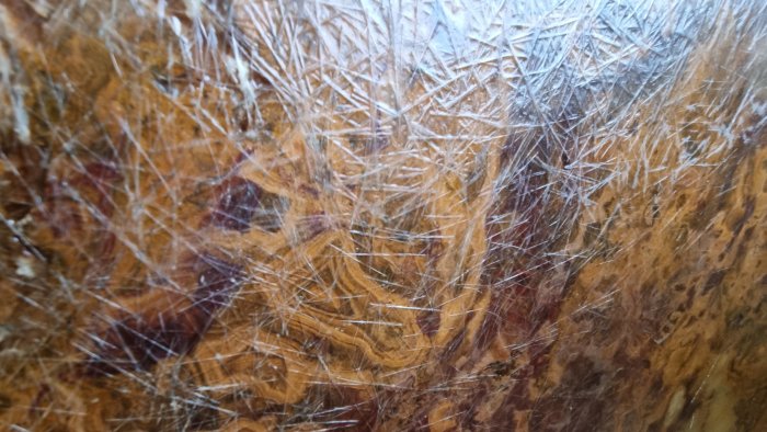 Grov textur, träyta med repor, naturlig mönster, detaljrik, mångfärgad, närbild, ingen synlig kontext.