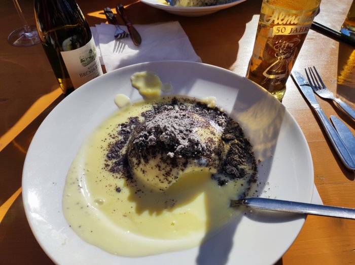 Germknödel med vallmofrön och vaniljsås, vinflaska, utomhus, solsken, måltid, dessert, bestick, glas.