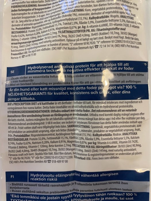 Etikett på kattfoder med näringsinformation och kontaktuppgifter. Texten är på svenska, delvis suddig.