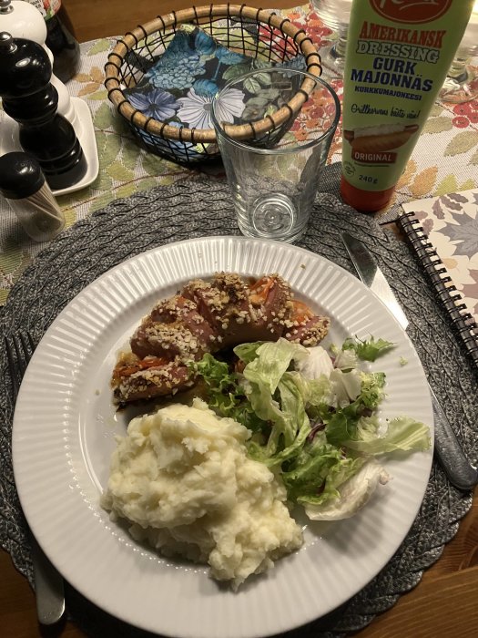 Middagstillbehör och noteringsblock på bordet. Potatismos, sallad, kryddat kött. Amerikansk gurkdressing. Salt- och pepparkvarn.