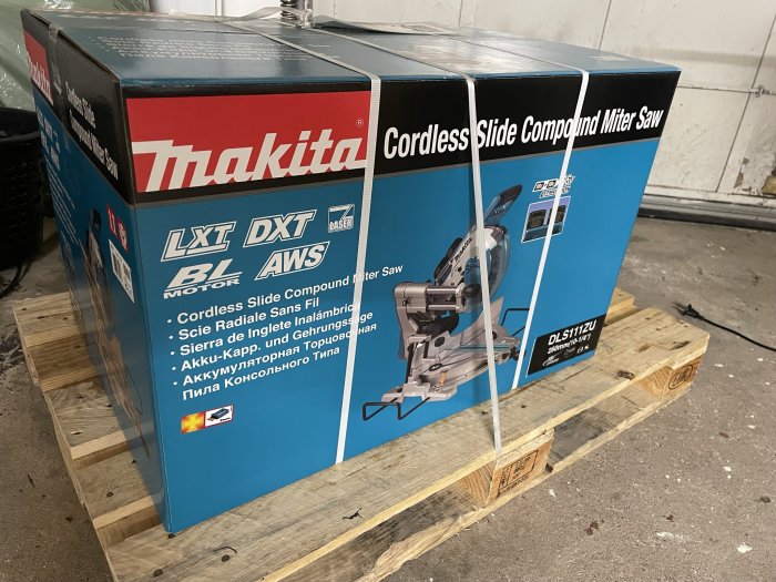 Tre förpackade Makita batteridrivna geringssågar på en träpall i ett lagerutrymme.