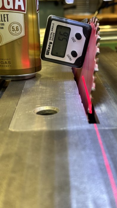 Digital vinkelmätare visar 45,0 grader på cirkelsåg. Precision, arbetsbänk, sågblad, röd laserlinje, verkstadsutrustning.