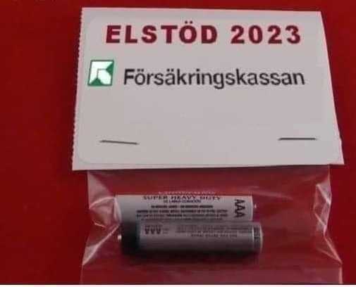 En skämtbild: texten "ELSTÖD 2023" och Försäkringskassans logotyp ovanför en ensam AA-batteri, antyder ironiskt minimalt stöd.