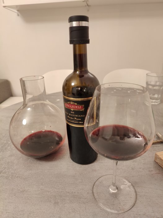 En flaska rött vin, dekanteringskärl och glas delvis fyllt med vin.