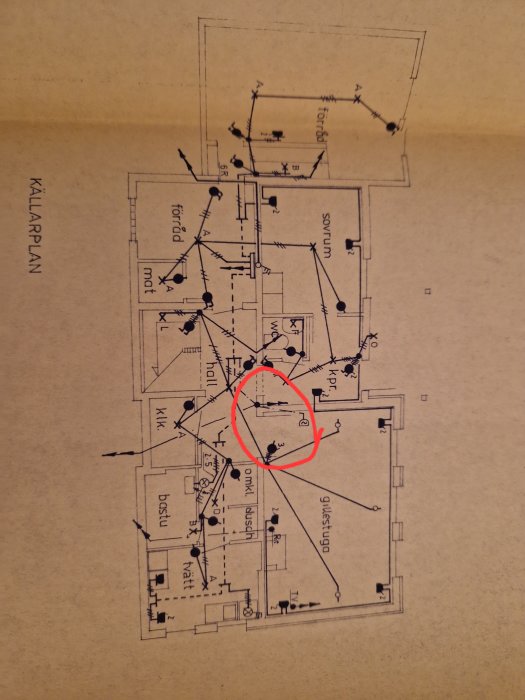 Arkitektonisk ritning eller planlösning för en källarvåning markerad med röd cirkel.