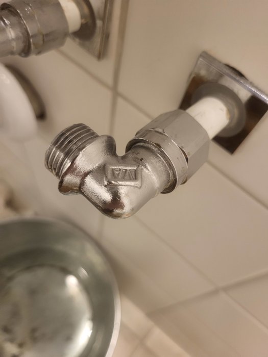 Vattenkran med hjärtformad anslutning, silverfärgad, mot kakelvägg, närbild.