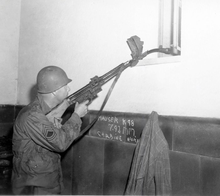 Soldat med hjälm siktar gevär genom fönster; gammalt fotografi, Mauser K98 skrivet, jacka hänger.