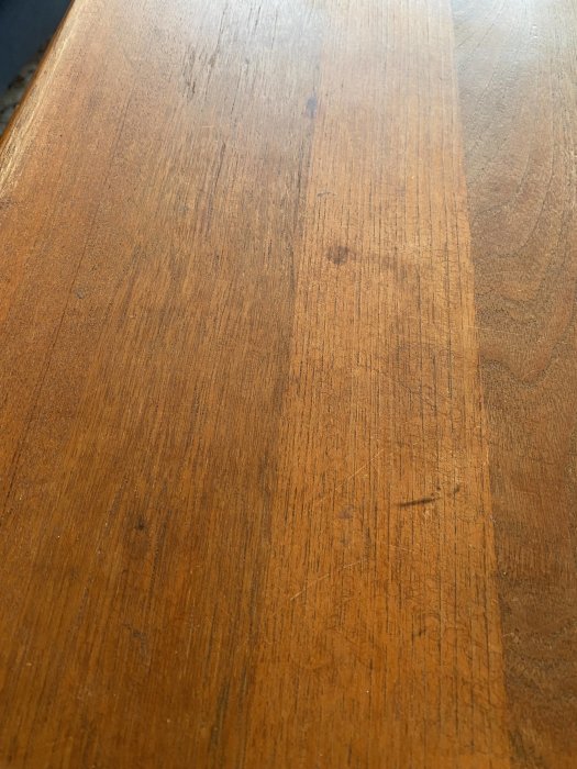 Träyta med brun nyans, slitage och repor, möjligtvis ett möbelstycke som bord.