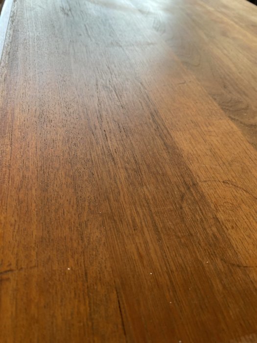 Trägolv eller bord, mörkbrun yta, textur synlig, närbild, perspektiv längs ytan.