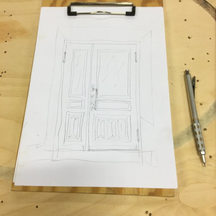 En blyertsteckning föreställande en dubbeldörr på ett papper, med ett sudd och en penna bredvid.