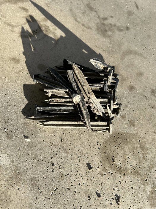 Trasig träkista på betonggolv med lång skugga i solljus.