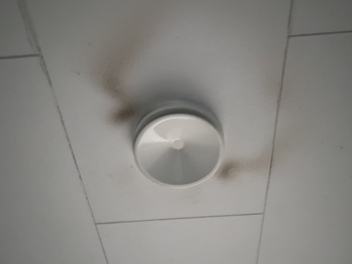 Rökgivare i tak med synlig smuts och sotfläckar runtomkring.