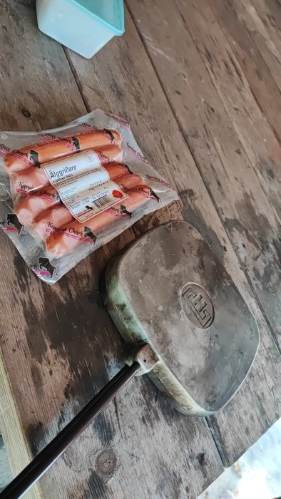 Förpackad korv, strykjärn på trägolv, smutsig, gammal, sladd, inköpsförpackning, köksartiklar, vardagliga föremål.