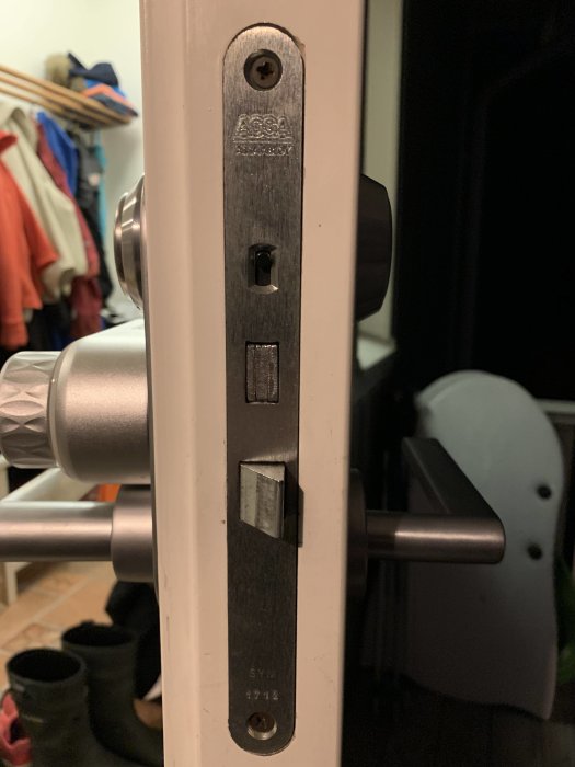 Ett lås på dörrhandtaget, med märkningen ASSA, silverfärgat, inne i ett hem.