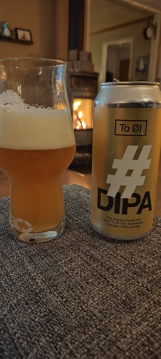 Ett glas öl framför en öppen eld, bredvid en burk med texten "DIPA".