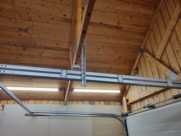 Träväggar och tak i ett garage, metallkonstruktioner, garageportmekanism och långsmala fönster för ljusinsläpp.