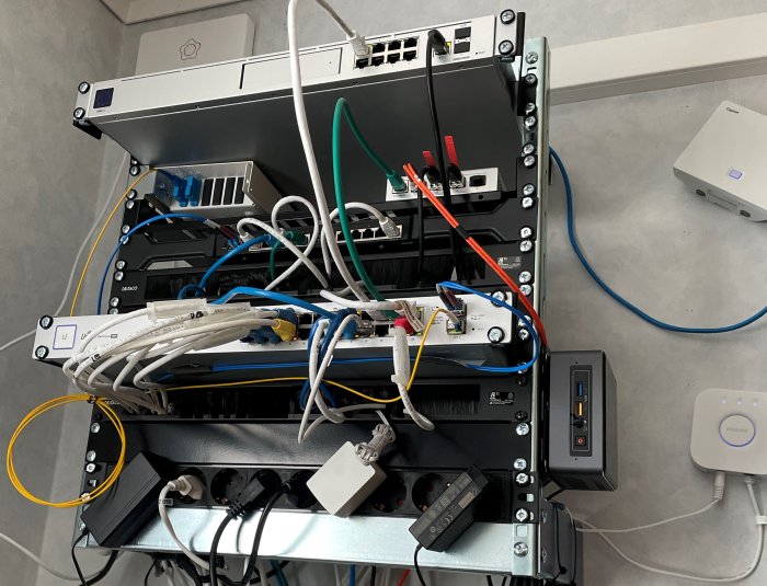 Nätverksutrustning och kablar monterade på vägg i ett teknikrum.