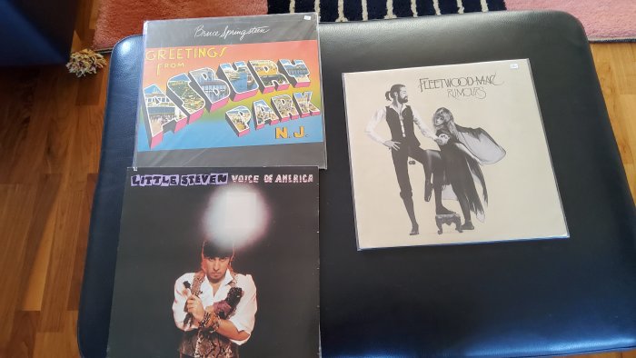Tre skivomslag på en stol. Rockmusik. Färgglada och ikoniska. Heminredning som bakgrund. Vinylskivor. Vintage-känsla.