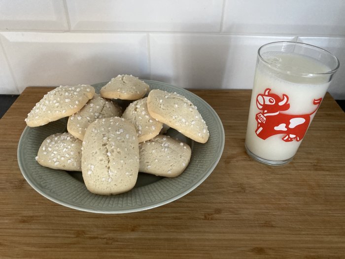 Kakor på fat, mjölk i glas med ko-motiv, köksbänk, enkel hemmiljö.