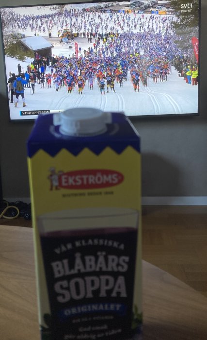 TV visar Vasaloppet 2023, förpackningar av blåbärssoppa i förgrunden, skidtävling, svenskt vinteridrottsevenemang.