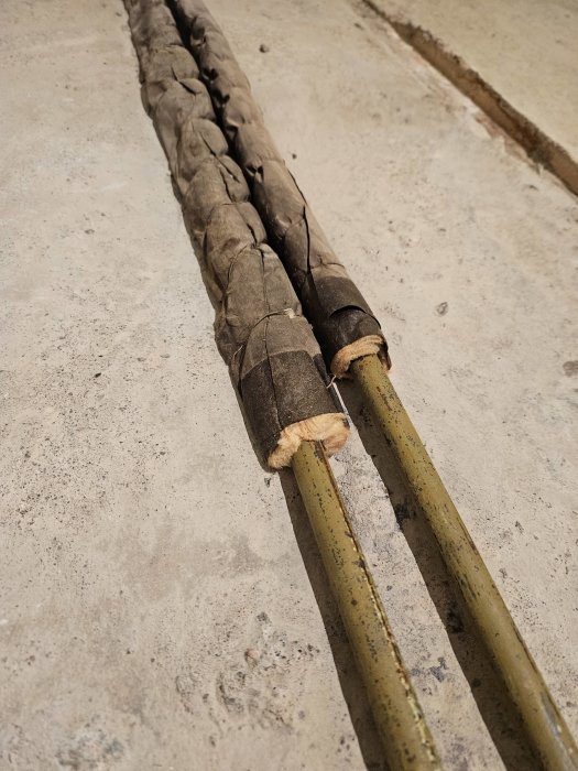 Gammal repbunden ledning eller slang på grå betongyta.