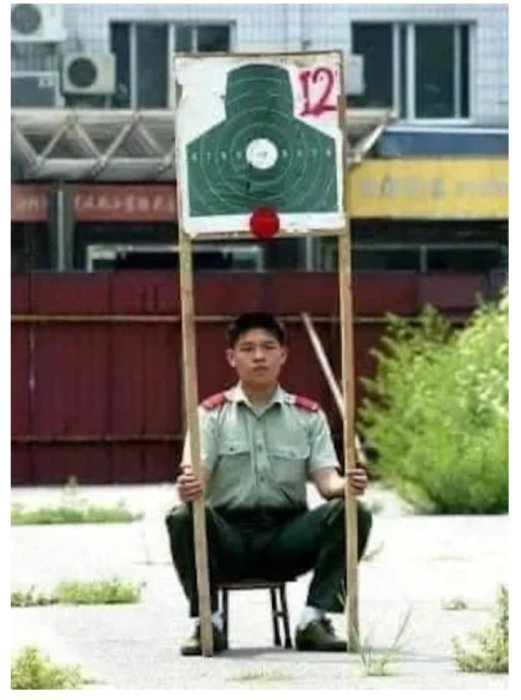 Person sittandes på stol håller konstgjord trafiksignal, improviserad, roligt, gatuomgivning, dagtid, kreativ lösning.