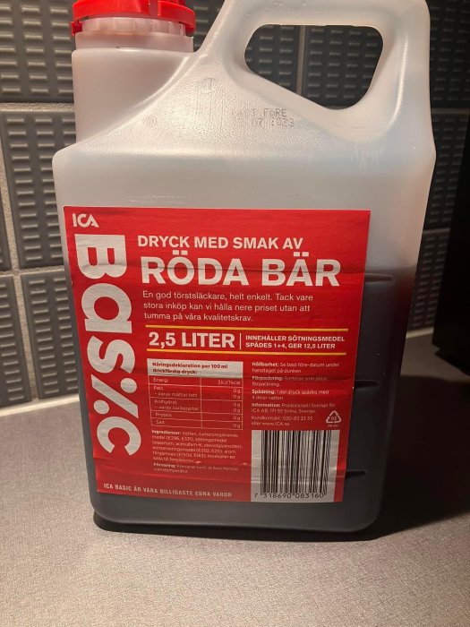 En stor plastdunk märkt ICA, innehåller 2,5 liter dryck med smak av röda bär.