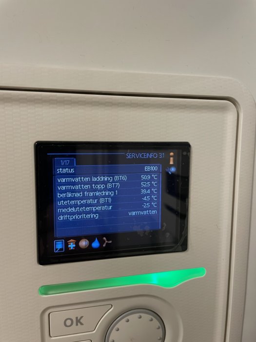 Digital display visar värmesystem-status, temperaturdata, och driftinställningar på en vit bakgrund med grönt lysande OK-knapp.